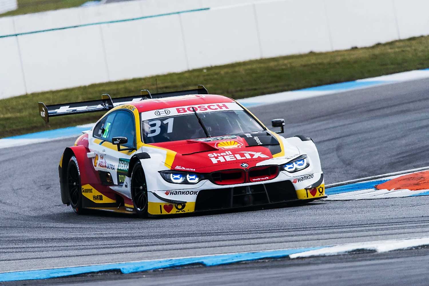 BMW M4 DTM con decoracion de Shell Helix girando en circuito durante una carrera demostrando potencia y precision en competicion