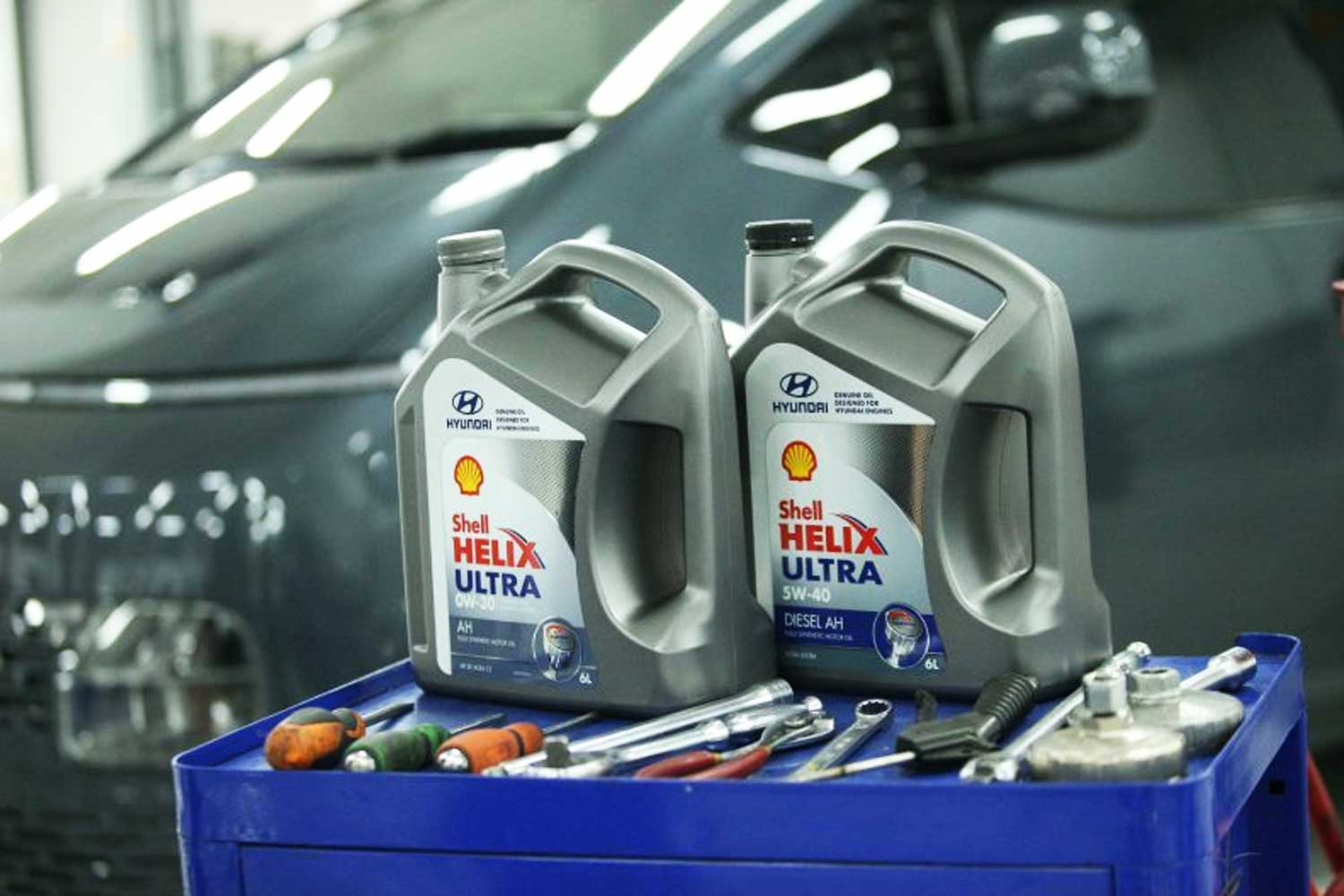 Bidones de aceite Shell Helix Ultra co brandeados con Hyundai sobre carro de herramientas en un taller mecanico listos para mantenimiento profesional